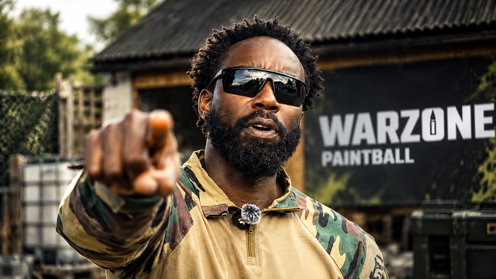 Le Colonel Varkon pointe la recrue du doigt, enseigne WARZONE PAINTBALL en arriere-plan